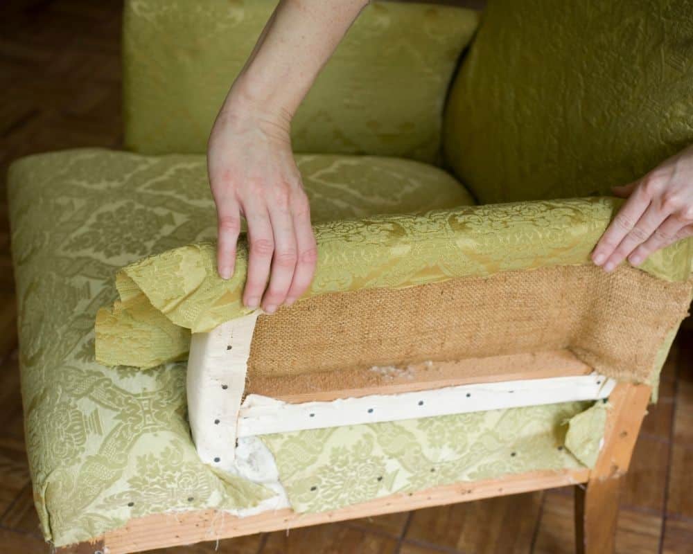 Close up view of a woman reupholstering a chair.