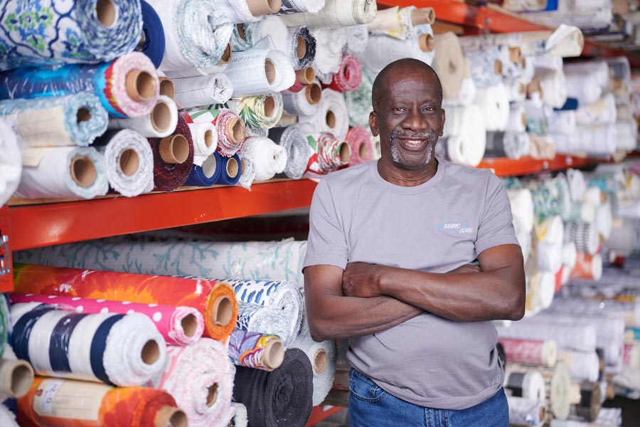 Photo showing employee standing in front of extensive fabric selection